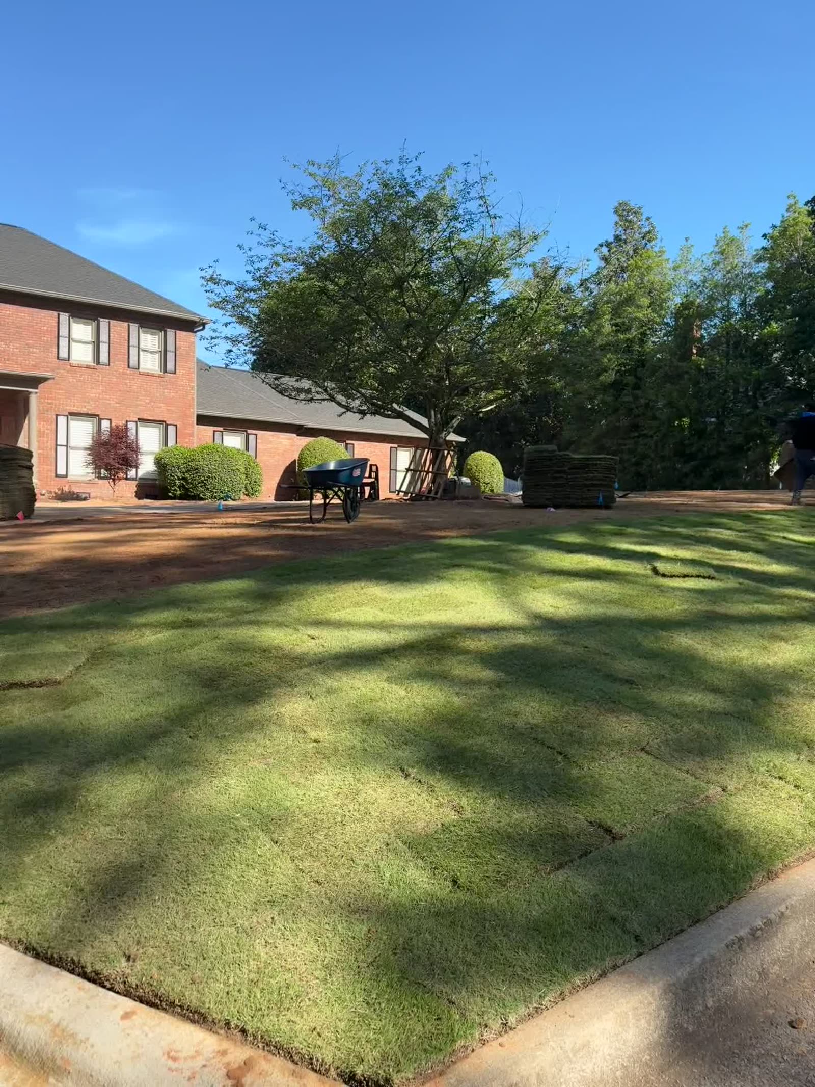 Freshly sodded front yard with pallets staged for installation